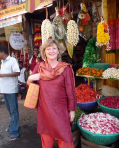Etna Marx - Coach und Persönlichkeitsentwicklerin im roten Gewand auf einem Markt in Indien